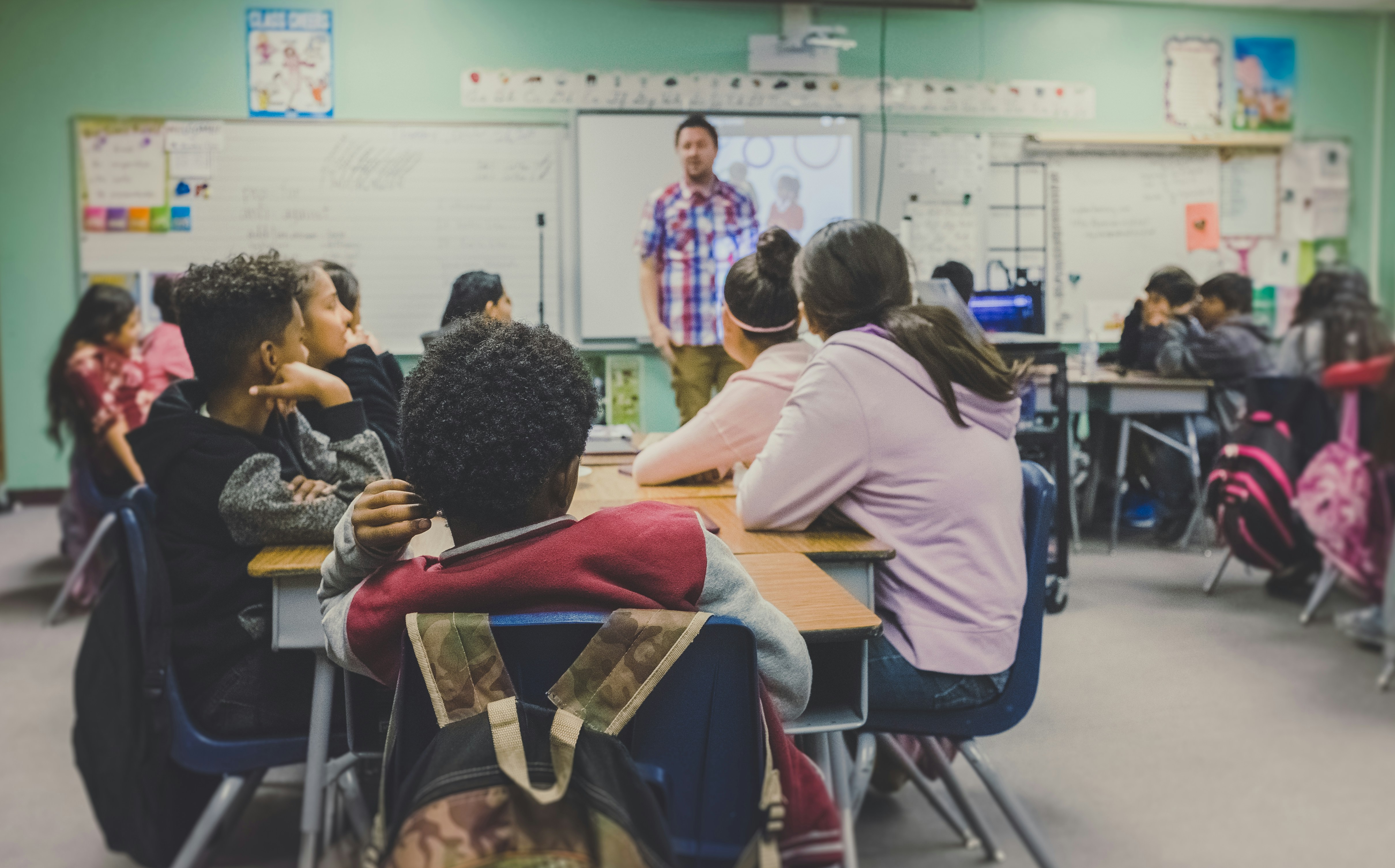 Students listen to their teacher in a classroom. 