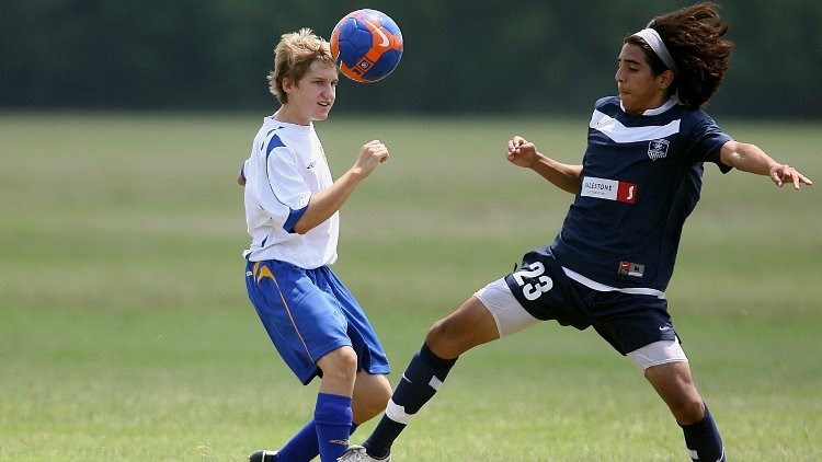Two young people playing soccer