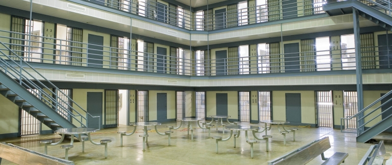 The central area of a prison, showing several metal tables and three floors of cells.