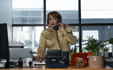 A transfeminine executive using the phone in her office with a pen