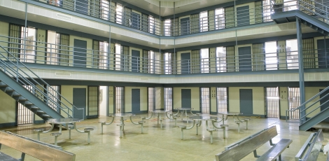 The central area of a prison, showing several metal tables and three floors of cells.